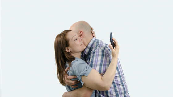 Man and women hugging - woman looking at phone